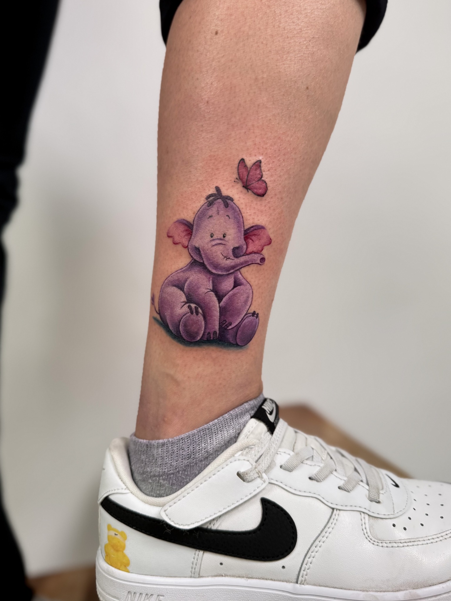 Violettes Elefantenmotiv mit Schmetterlingen als farbiges Tattoo am Unterschenkel