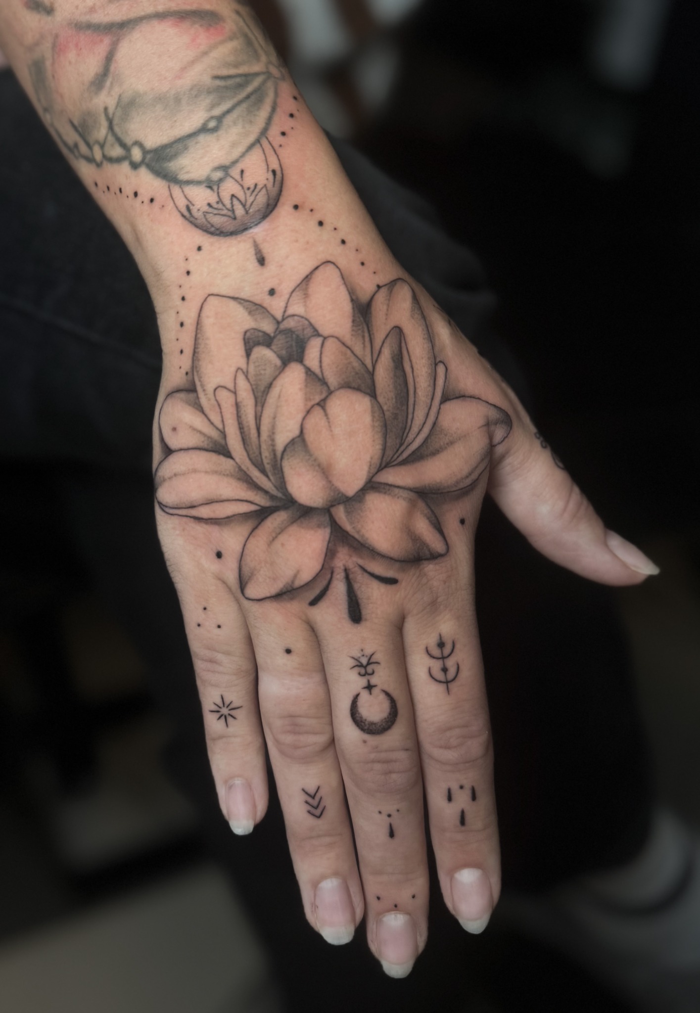 Lotusblüte auf dem Handrücken mit filigranen Symbolen und Ornamenten auf den Fingern