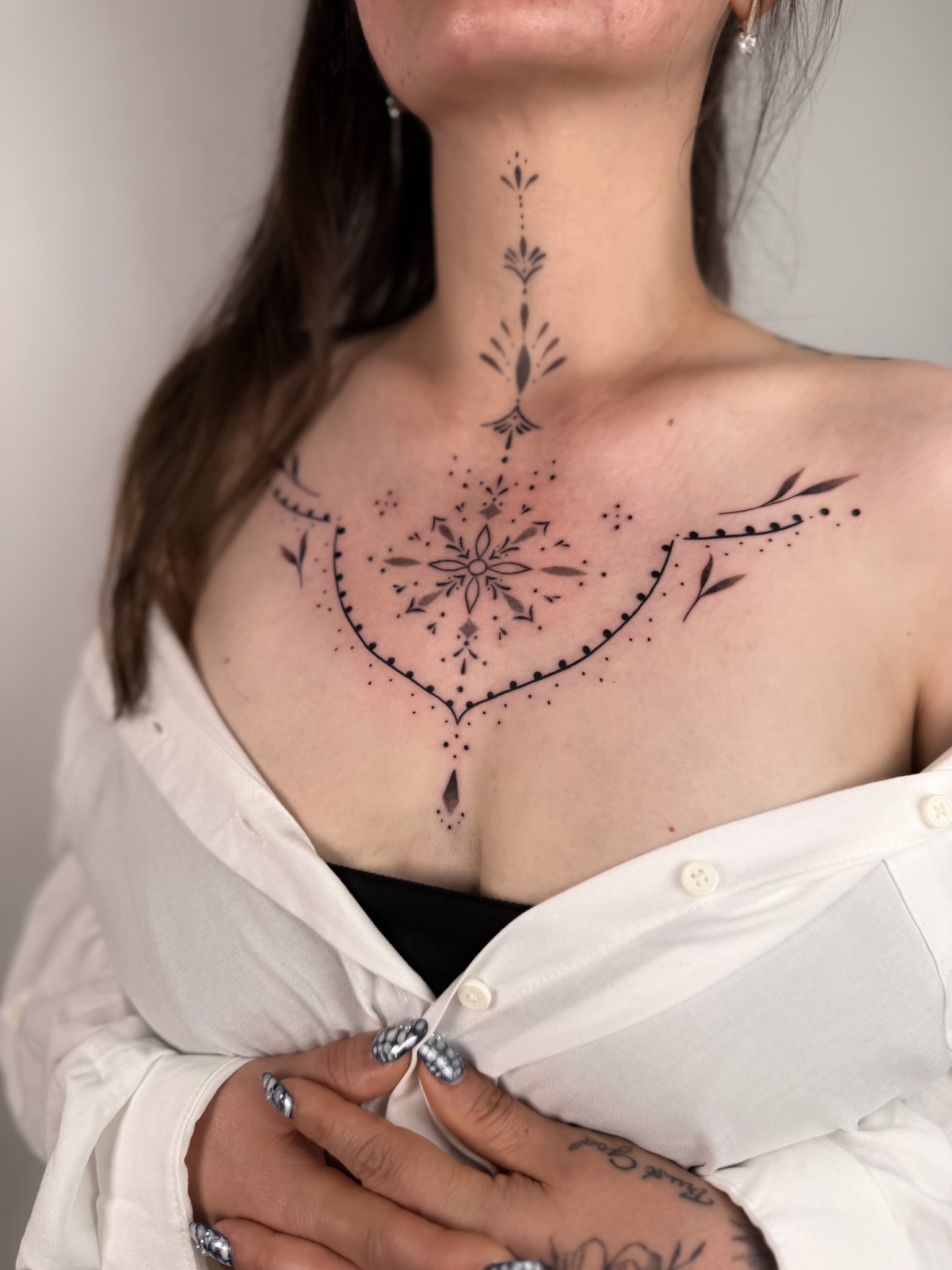 Filigranes Ornamental Tattoo am Dekolleté mit zentralem Blütenmotiv und Verlauf zum Hals