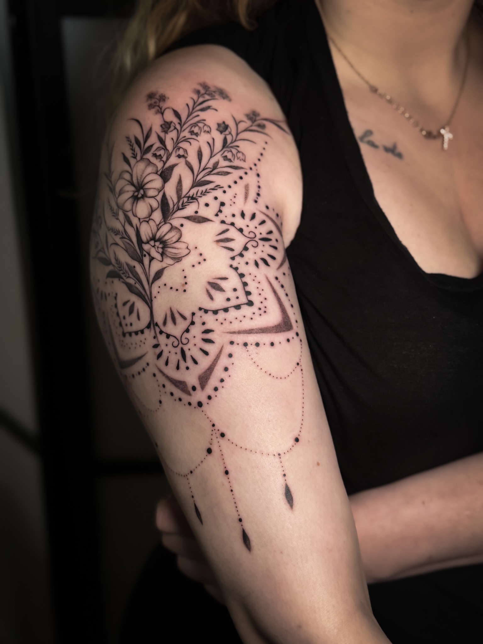 Ornamental Tattoo an Schulter und Oberarm mit Blättern und herabhängenden Punktlinien