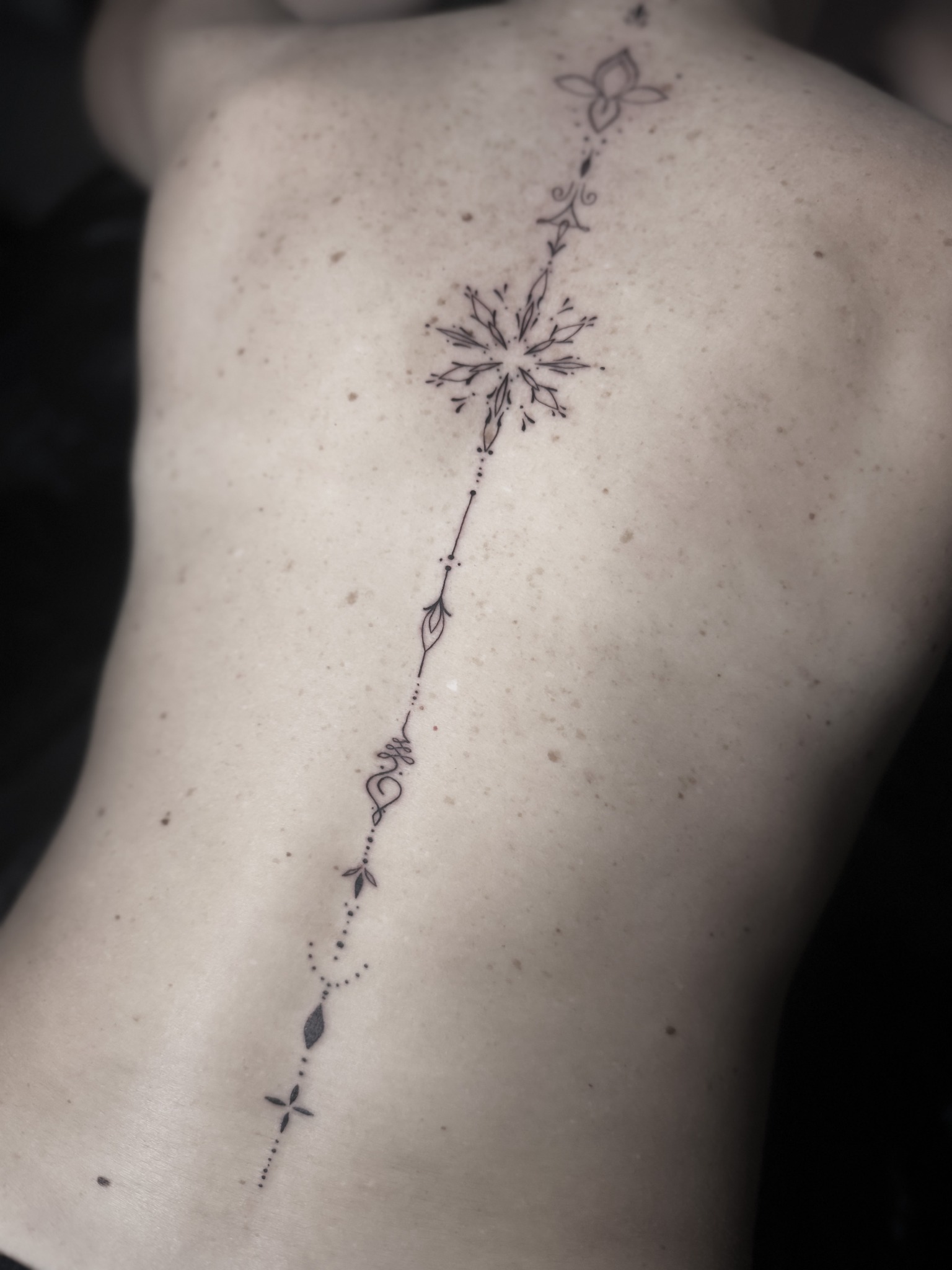 Filigranes Ornamental Tattoo entlang der Wirbelsäule mit zentralem sternförmigem Motiv
