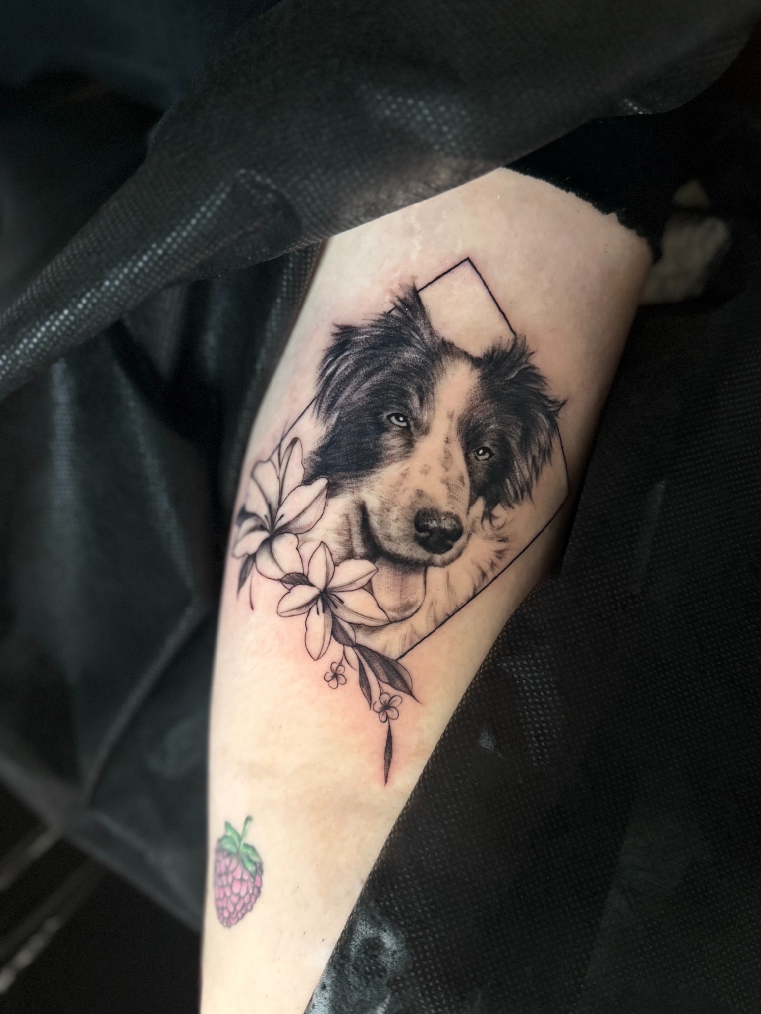 Hundeporträt in Black & Grey am Unterarm mit Blumen und geometrischem Rahmen
