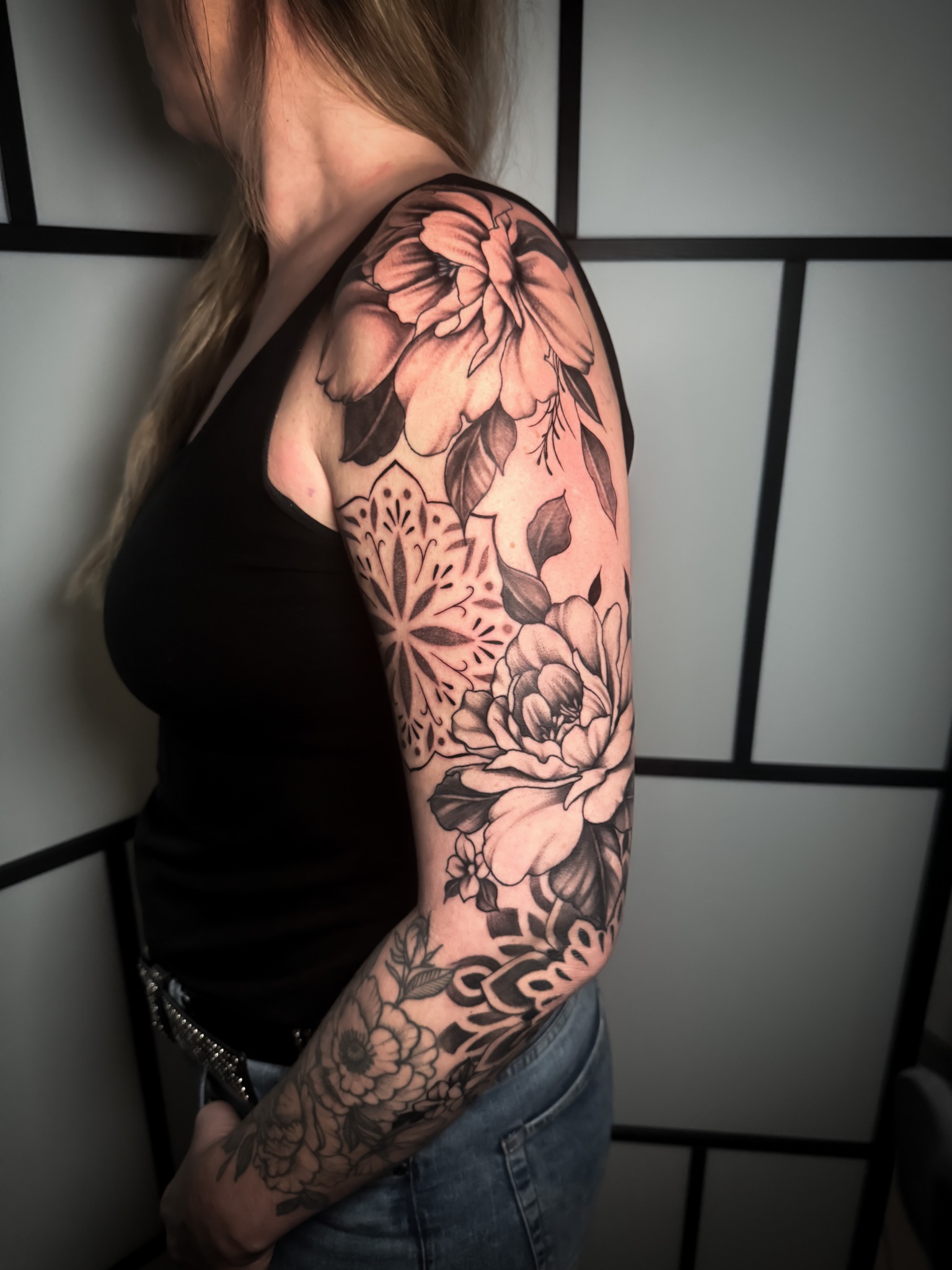 Großflächige Tattoo-Komposition am Arm mit Blumen, Blättern und ornamentalen Mustern